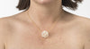 An image of a white snowball pearl cluster necklace on a gold chain on a woman's neck