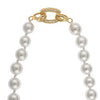 A close-up of a white pearl necklace with a decorative gold and crystal clasp